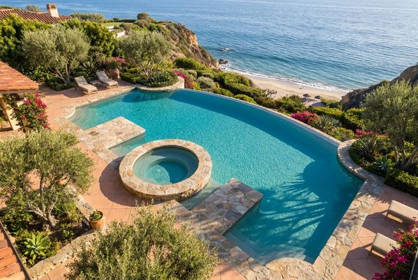 Aerial view of a geometric saltwater pool with an attached spa and deck