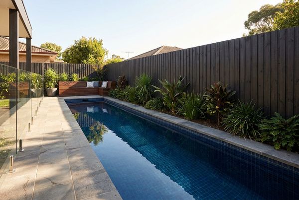 Narrow lap pool running along a fence line beside a modern house