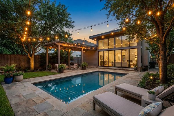 Small backyard pool lit by string lights at dusk