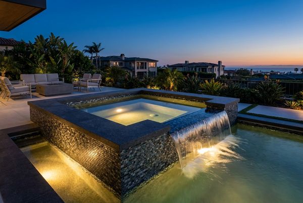 Spillover spa lit warmly at dusk with a glowing spillway