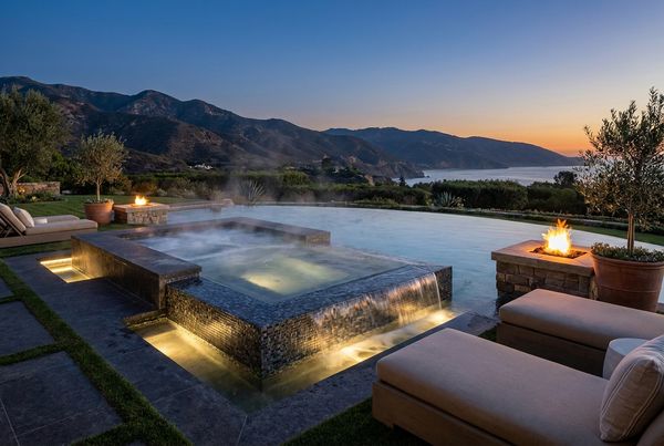 Spillover spa lit warmly at dusk with glowing spillway