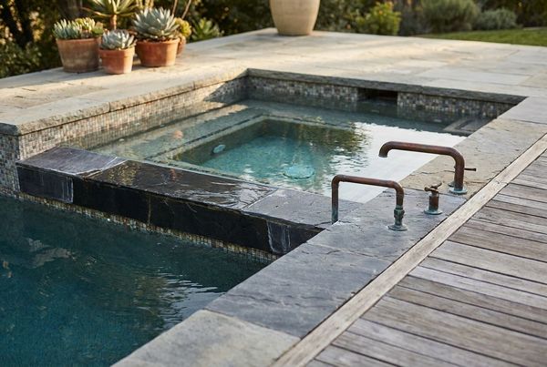 Modern spool pool with a raised spa spilling into it