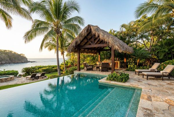 Thatched tiki hut beside a tropical pool