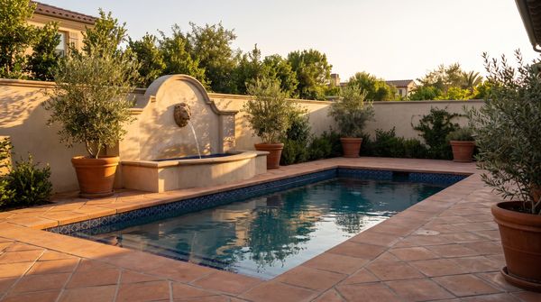 Mediterranean courtyard pool with terracotta pavers and a wall fountain