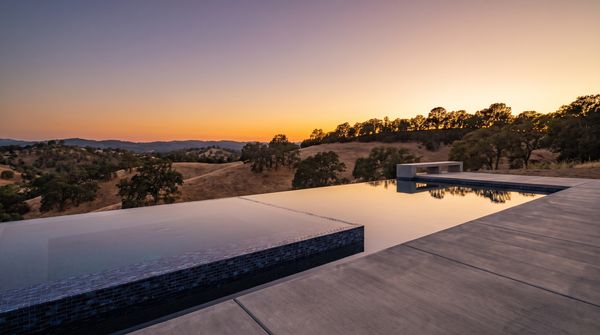 Modern infinity-edge swimming pool overlooking rolling hills at sunset